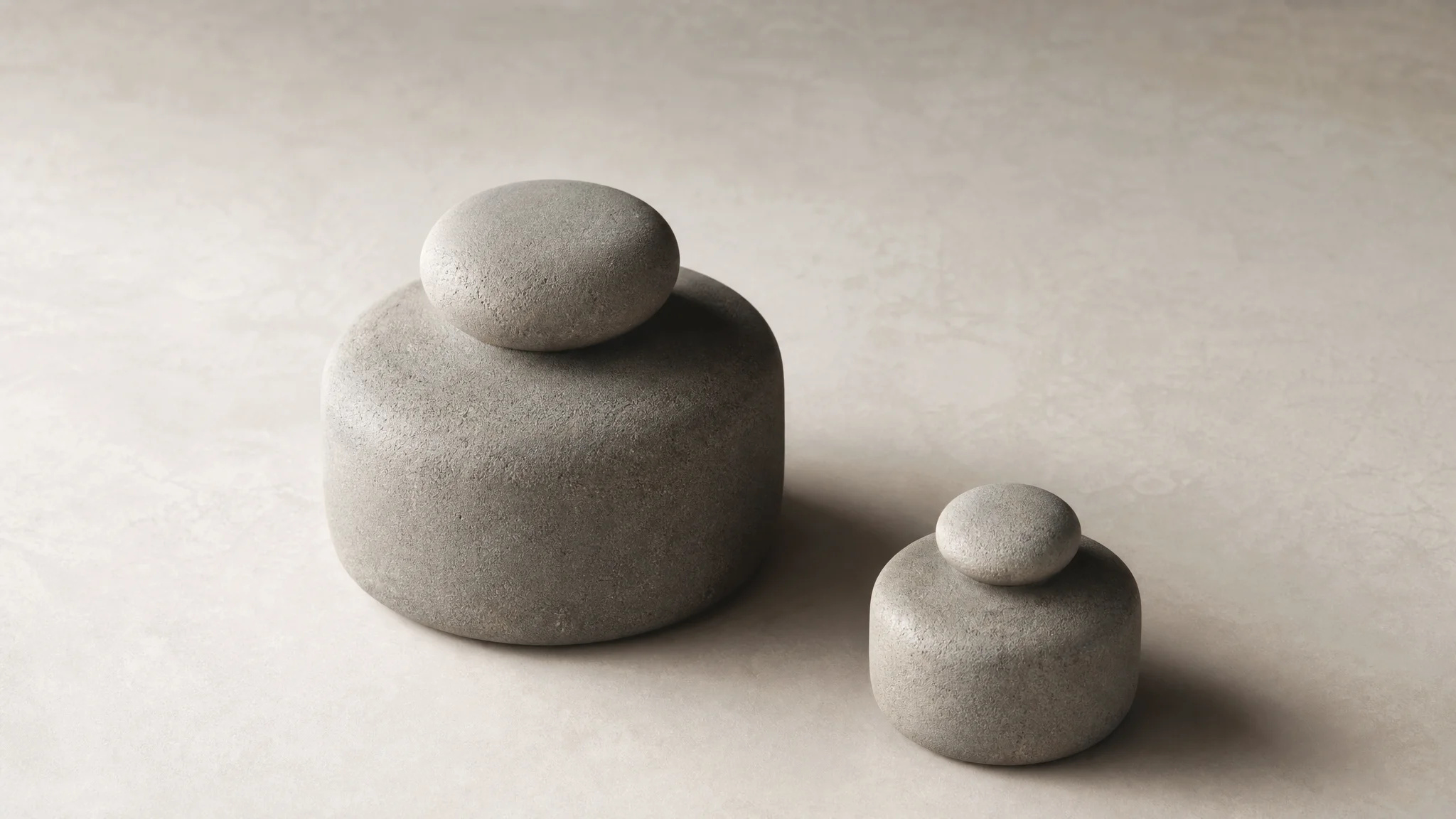 Two unevenly sized stone weights resting side by side on a plain surface, illustrating a deliberate, uneven balance rather than an equal split.