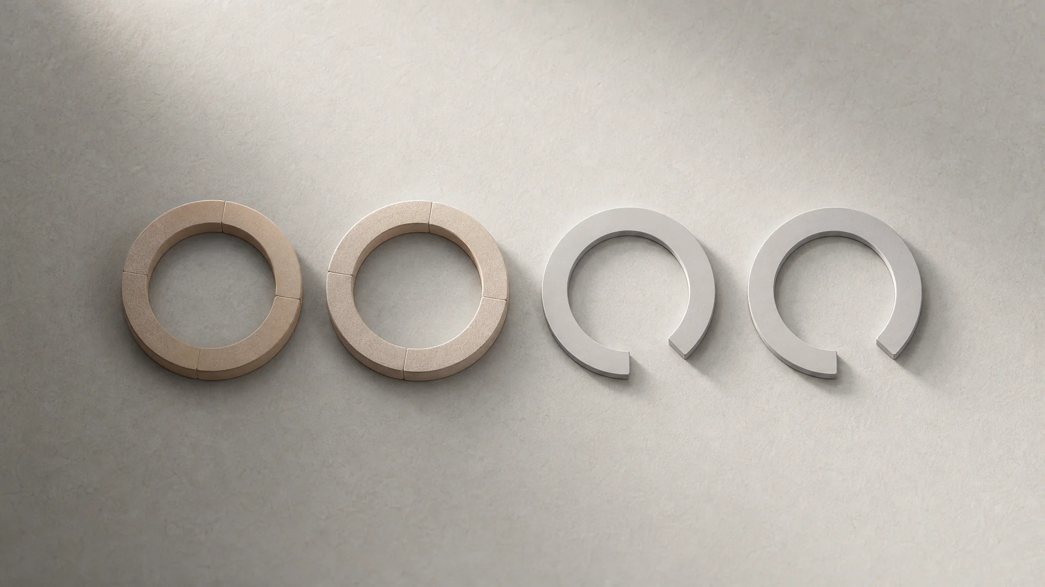 Four abstract circular loops on a neutral surface, two shown as complete unbroken rings and two as partial arcs with visible gaps.